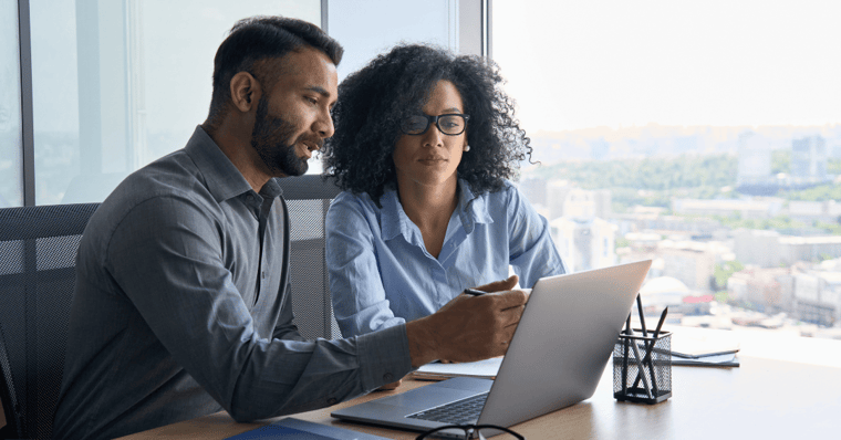 male and female worker using laptop sitting in modern office near panoramic window.