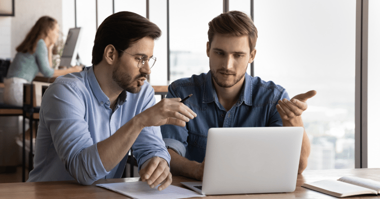 Office employees discussing project at a laptop