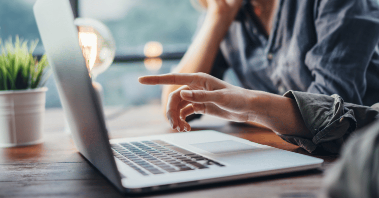 a person showing another person something on a laptop by pointing to the screen