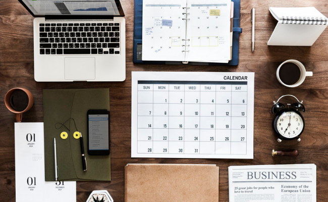 Desk with laptop calendar notebook mobile and pens