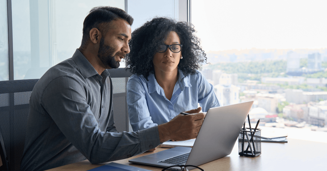 male and female workers using laptop sitting in modern office near panoramic window