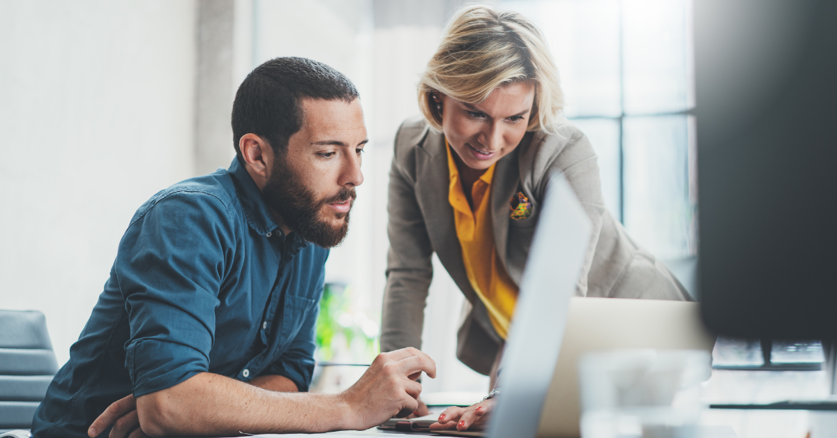 two business people gather near a laptop